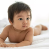 Baby boy tummy time on a clean white sheet